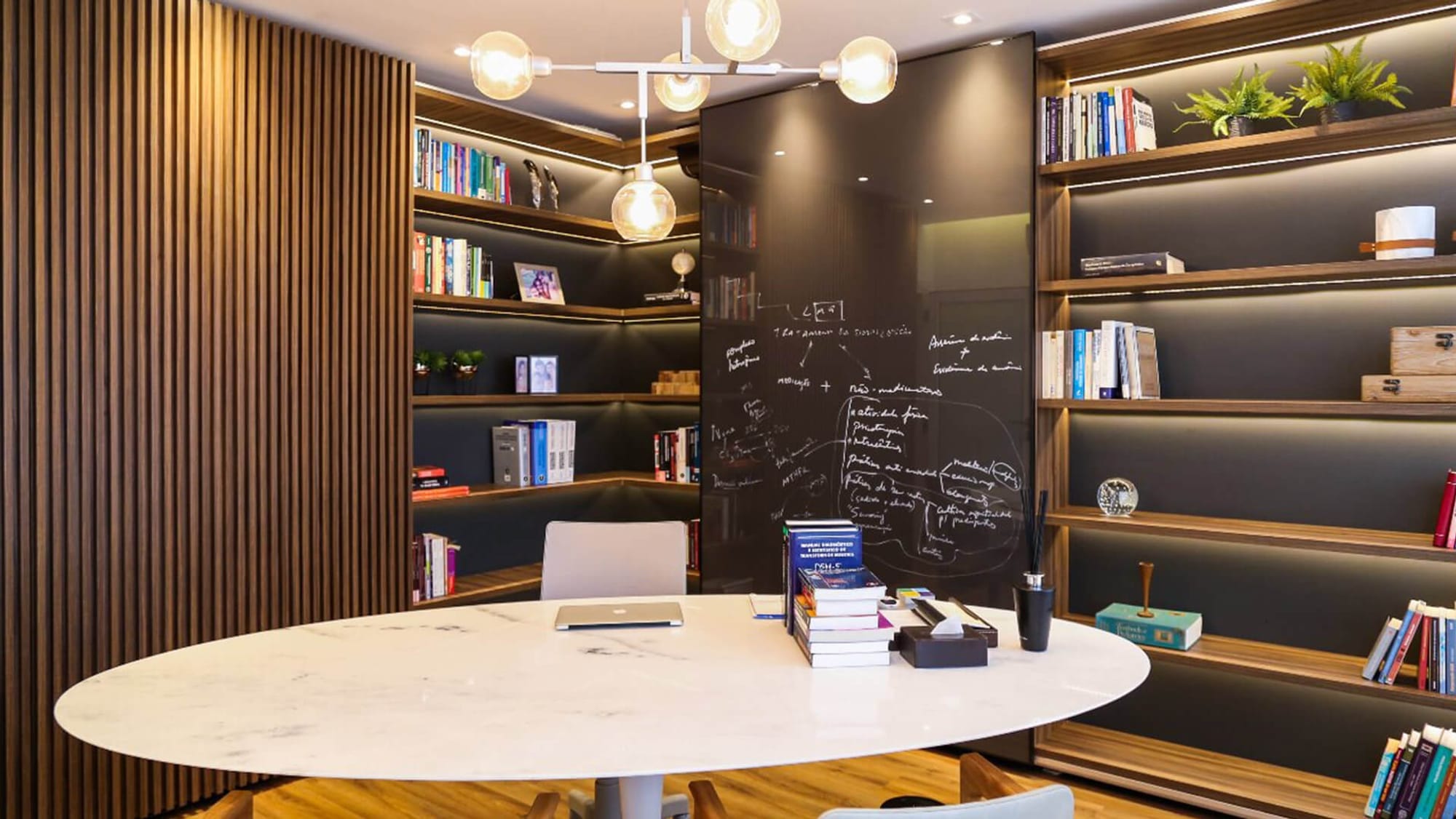 Sala de atendimento com mesa de mármore e biblioteca